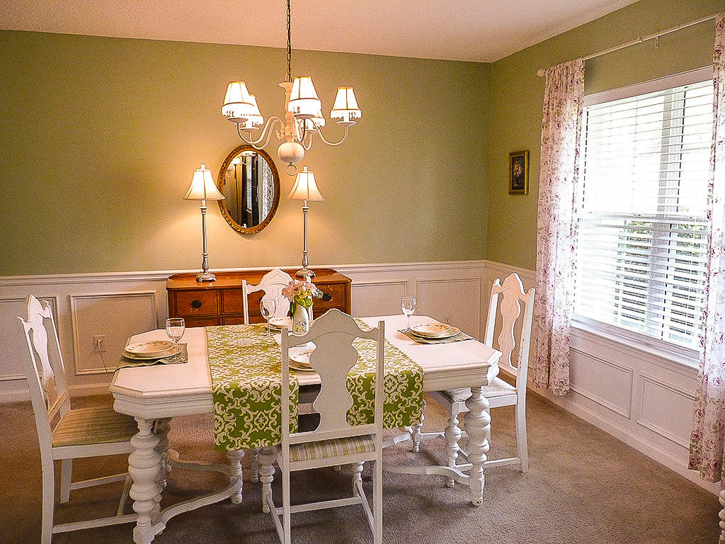 Dining room with green walls and white table and chairs set