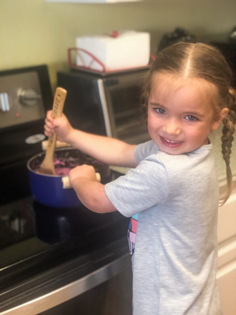 little girl stirring something on the stove
