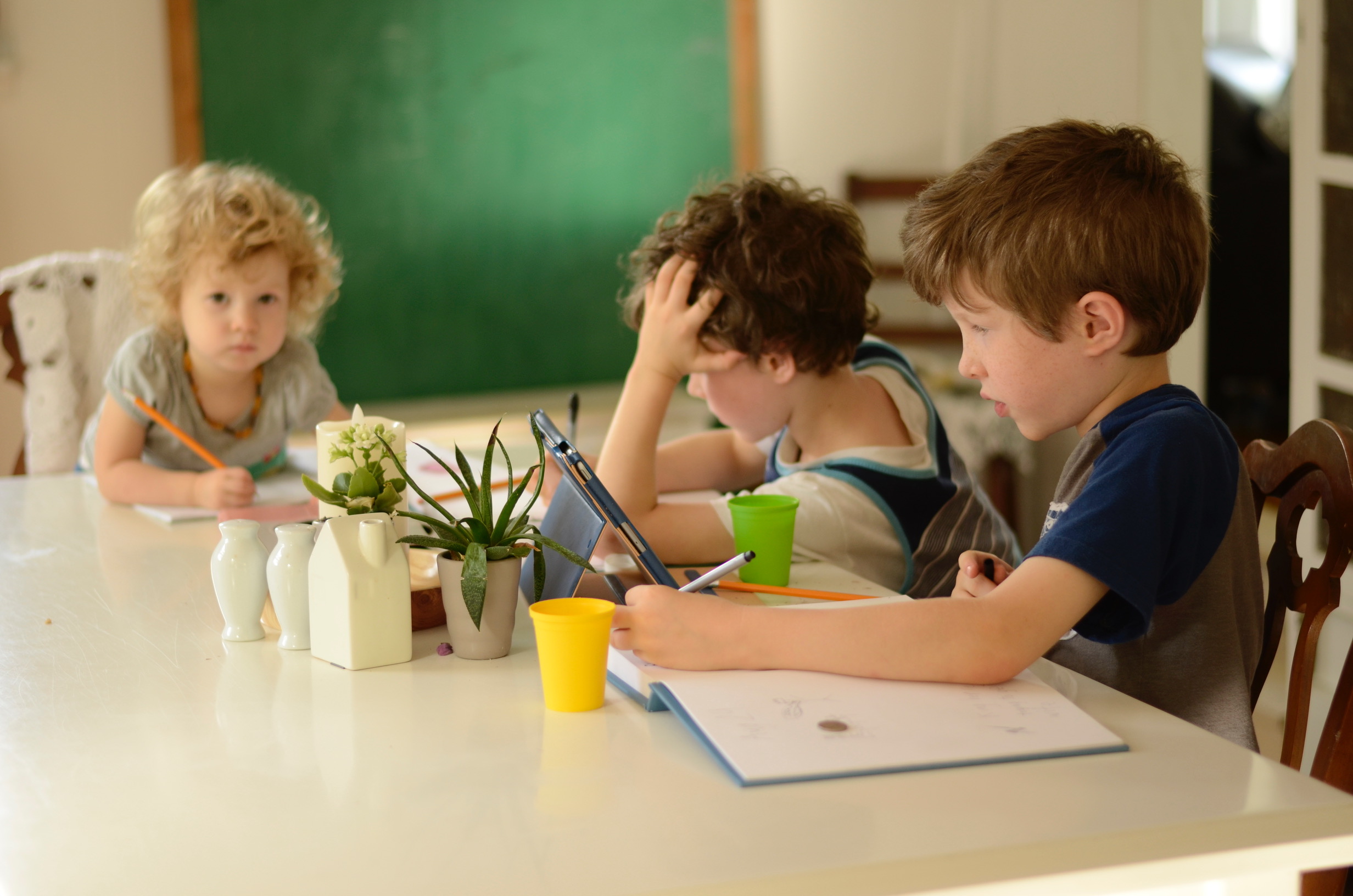 three children doing schoolwork at a table