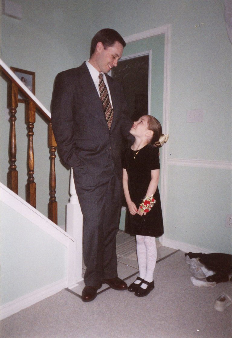 A father and small daughter, dressed up, prepare to go out for a special date.